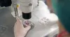 Ręka w rękawiczce umieszcza próbkę w mikroskopie w laboratorium