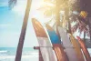 Deski surfingowe ustawione na plaży przy palmach nad morzem